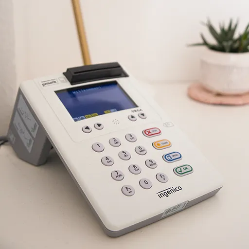 Ein modernes Kartenlesegerät auf einem Holzschreibtisch für die einfache Bezahlung von Therapiesitzungen per Karte oder App.