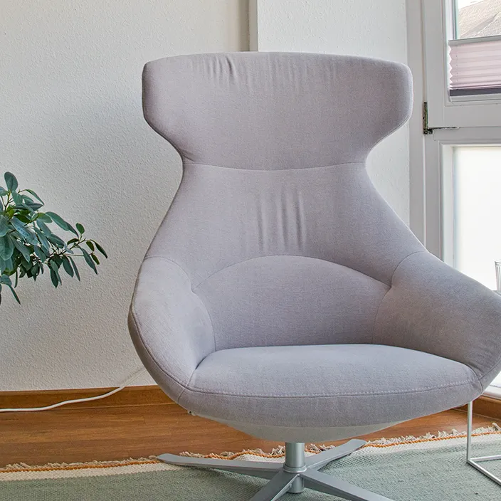 Ein bequemer, grauer Sessel in einem ruhigen Einzeltherapieraum, der für ungestörte Gespräche eingerichtet ist.