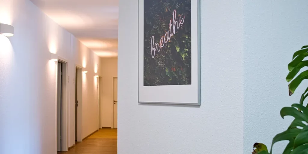 Heller Flur einer Psychotherapie-Praxis mit warmem Licht und einem gerahmten Bild mit der Aufschrift breathe.