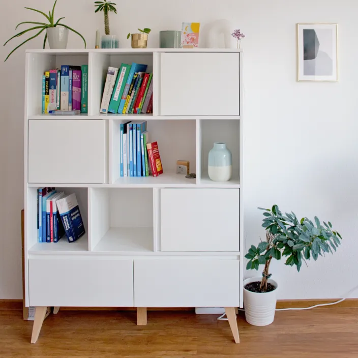 Ein gut organisiertes weißes Regal mit verschiedenen Fachbüchern über Psychologie, Therapie und persönliche Entwicklung in einer Praxis.